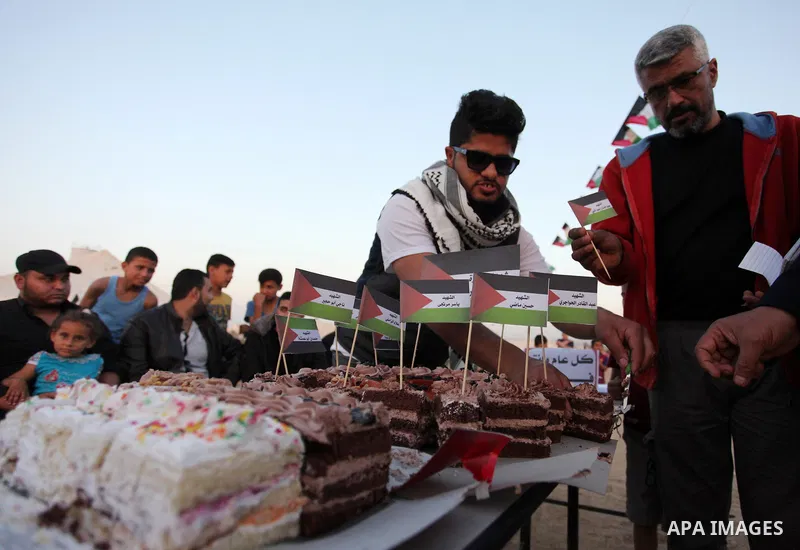 Palestinians cut cake during a protest at the Israel-Gaza border where Palestinians demand the right to return to their homeland, east of Gaza City April 19, 2018. Photo by Mahmoud Ajour