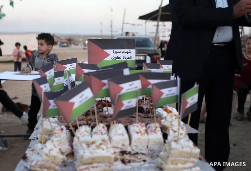 Palestinians cut cake during a protest at the Israel-Gaza border where Palestinians demand the right to return to their homeland, east of Gaza City April 19, 2018. Photo by Mahmoud Ajour