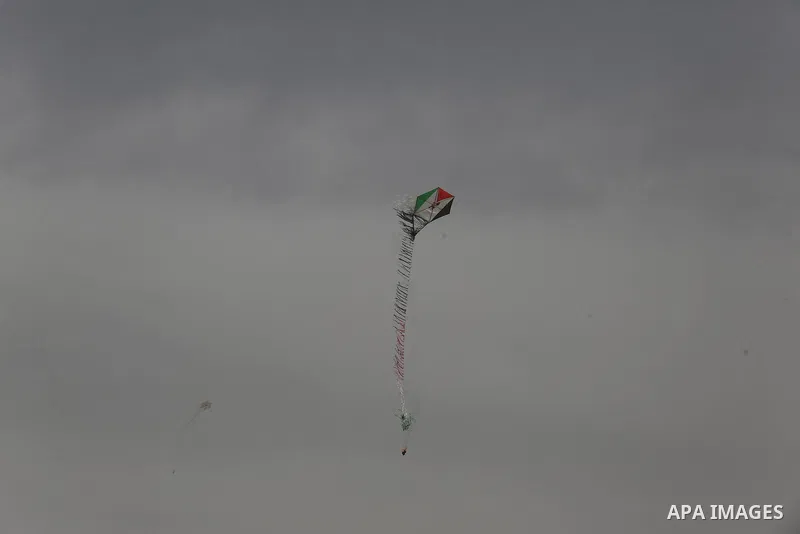 A picture taken on April 20, 2018 shows a kite laden with a molotov cocktail being flown by Palestinian youths over the border with Israel before cutting the string across the fence, during clashes with Israeli security...