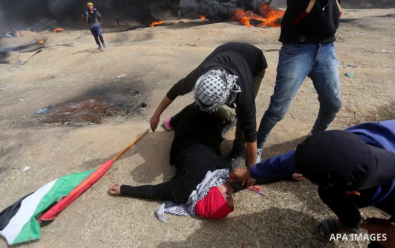 A Palestinian woman reacts to a tear gas during clashes with Israeli security forces at tents protest at the Israel-Gaza border where Palestinians demand the right to return to their homeland, in east of Gaza city on Apr...