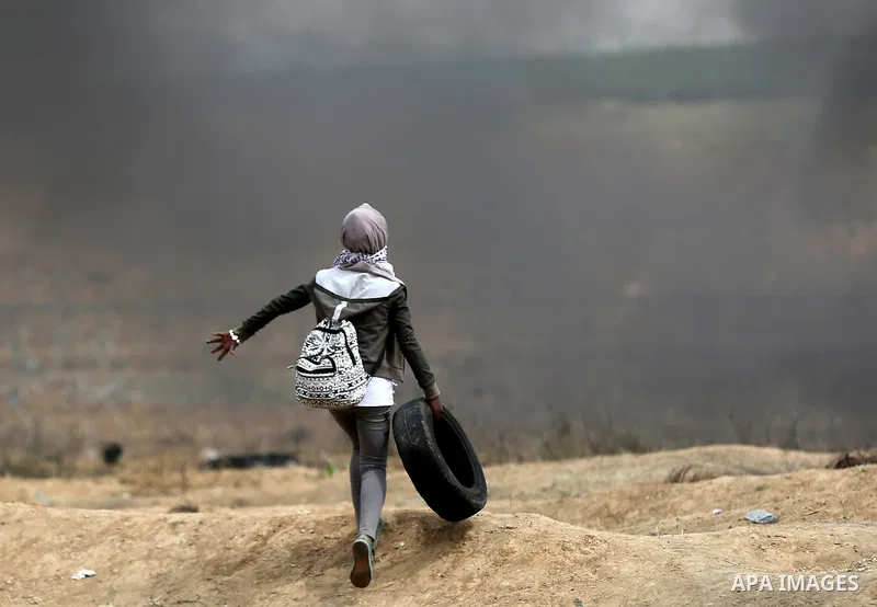 A Palestinian girl carries a tire during clashes with Israeli security forces at tents protest at the Israel-Gaza border where Palestinians demand the right to return to their homeland, in east of Gaza city on April 20,...
