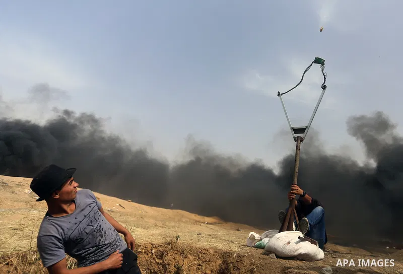 Palestinian protesters use a large slingshot to hurl stones during clashes with Israeli security forces at tents protest at the Israel-Gaza border where Palestinians demand the right to return to their homeland, in east...
