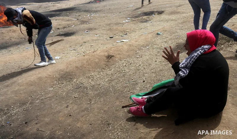 A Palestinian woman reacts to a tear gas during clashes with Israeli security forces at tents protest at the Israel-Gaza border where Palestinians demand the right to return to their homeland, in east of Gaza city on Apr...