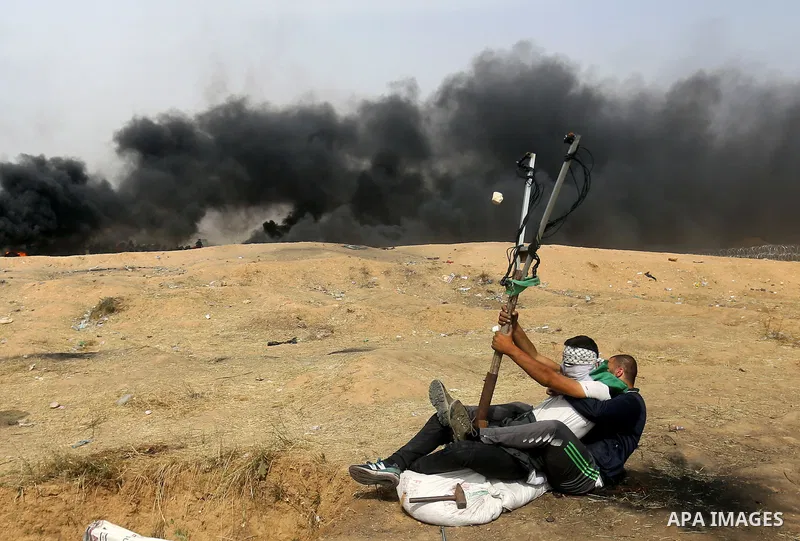 Palestinian protesters use a large slingshot to hurl stones during clashes with Israeli security forces at tents protest at the Israel-Gaza border where Palestinians demand the right to return to their homeland, in east...