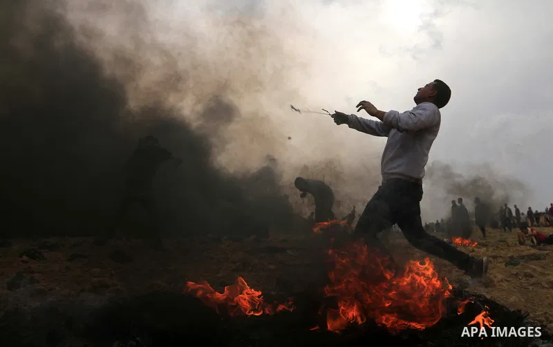 A Palestinian proteste uses a slingshot to hurl stones during clashes with Israeli security forces at tents protest at the Israel-Gaza border where Palestinians demand the right to return to their homeland, in Bureij in...