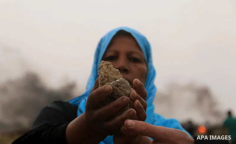 A Palestinian woman hurls stones towards Israeli security forces during clashes at tents protest where Palestinians demand the right to return to their homeland, at the Israel-Gaza border, in Bureij in the cetner of Gaza...