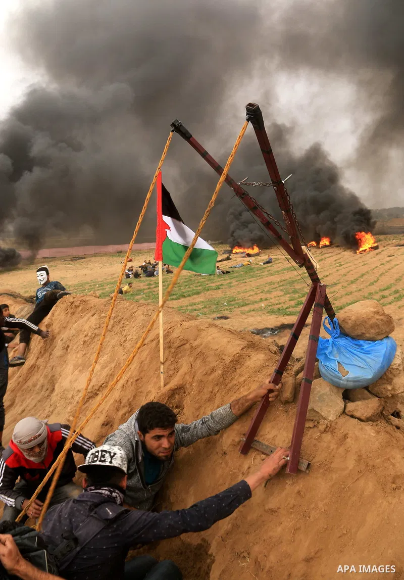 Palestinian protesters use a larag slingshot to hrul stones during clashes with Israeli security forces at tents protest at the Israel-Gaza border where Palestinians demand the right to return to their homeland, at the I...