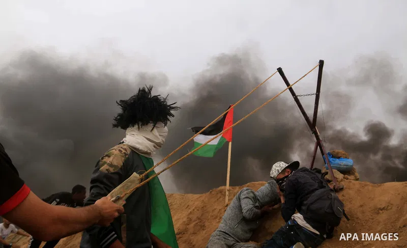Palestinian protesters use a larag slingshot to hrul stones during clashes with Israeli security forces at tents protest at the Israel-Gaza border where Palestinians demand the right to return to their homeland, at the I...