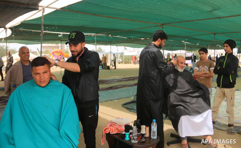 A Palestinian barber shaves the head during clashes with Israeli security forces at tents protest at the Israel-Gaza border where Palestinians demand the right to return to their homeland, in Bureij in the cetner of Gaza...