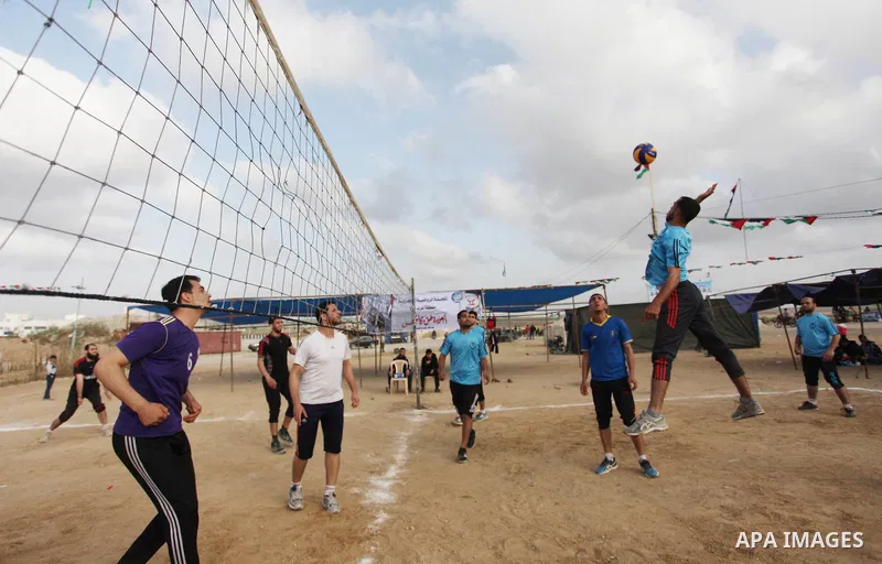 Palestinians play volleyball near tents during a tent city protest demanding the right to return to their homeland, at the Israel-Gaza border in the east of Gaza city on April 21, 2018. Photo by Mahmoud Ajjour