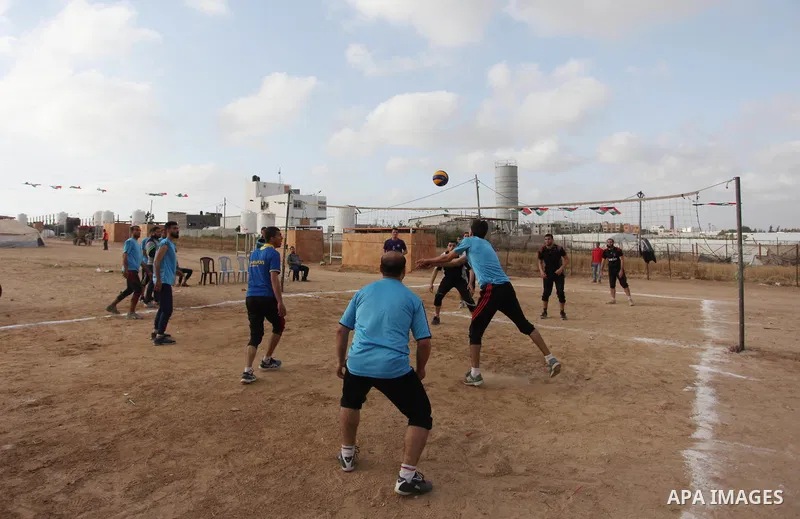 Palestinians play volleyball near tents during a tent city protest demanding the right to return to their homeland, at the Israel-Gaza border in the east of Gaza city on April 21, 2018. Photo by Mahmoud Ajjour