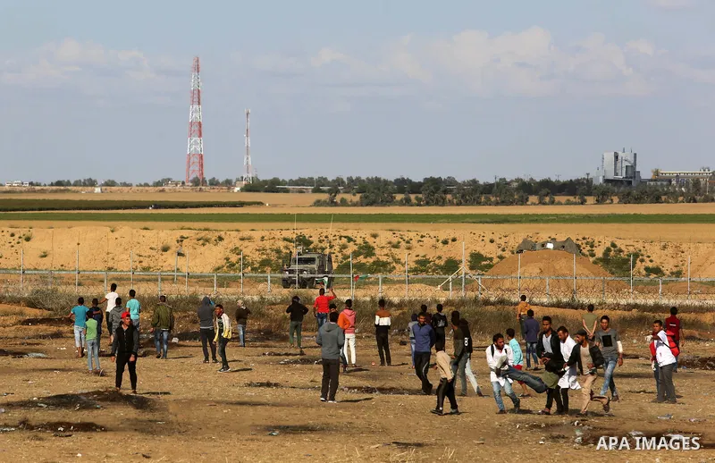 Palestinian demonstrators stand near the border fence with Israel near the southern Gaza Strip town of Khan Yunis during ongoing demonstrations on the Gaza-Israel border on April 22, 2018. Photo by Ashraf Amra