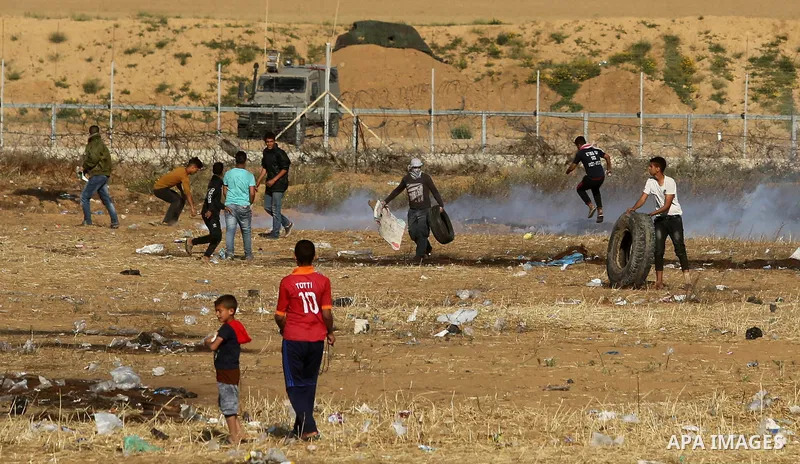 Palestinian demonstrators stand near the border fence with Israel near the southern Gaza Strip town of Khan Yunis during ongoing demonstrations on the Gaza-Israel border on April 22, 2018. Photo by Ashraf Amra