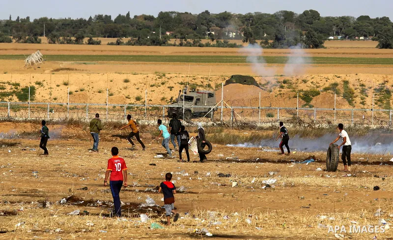 Palestinian demonstrators stand near the border fence with Israel near the southern Gaza Strip town of Khan Yunis during ongoing demonstrations on the Gaza-Israel border on April 22, 2018. Photo by Ashraf Amra