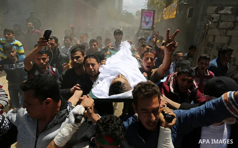 Mourners carry the body of a Palestinian deaf Tahreer Wahba, 18, who was died of from his injuries after being shot in the head by Israeli security forces during clashes on April 6, during his funeral in Khan Yunis, in t...