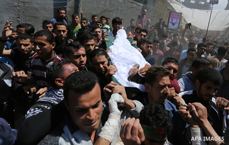 Mourners carry the body of a Palestinian deaf Tahreer Wahba, 18, who was died of from his injuries after being shot in the head by Israeli security forces during clashes on April 6, during his funeral in Khan Yunis, in t...