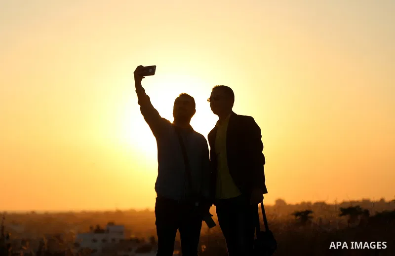 A Palestinian man takes a selfie during sunset near the Israel-Gaza border, east of Gaza city on April 23, 2018. Photo by Yasser Qudih