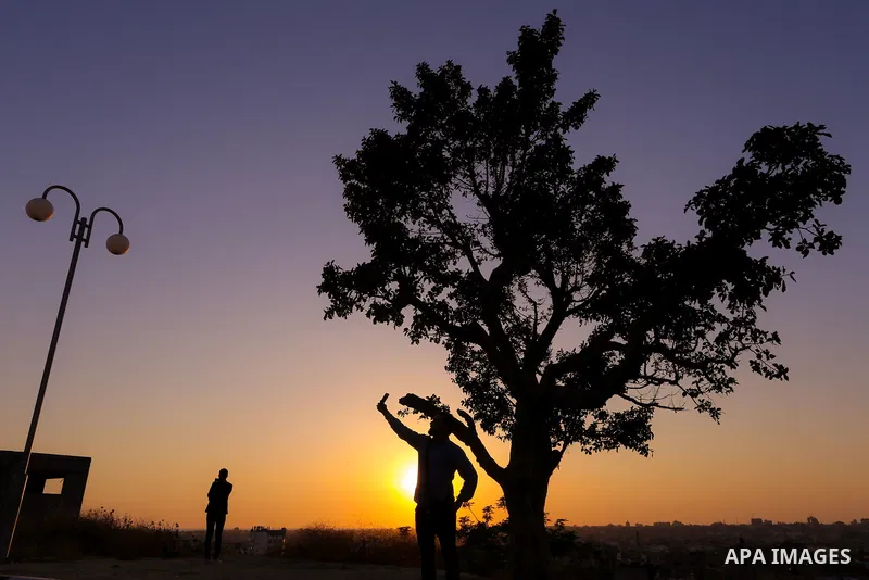 A Palestinian man takes a selfie during sunset near the Israel-Gaza border, east of Gaza city on April 23, 2018. Photo by Yasser Qudih