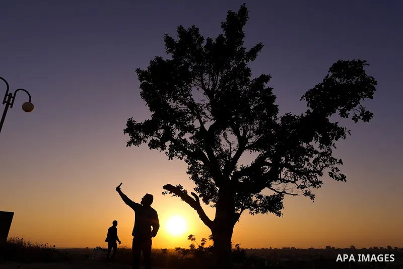 A Palestinian man takes a selfie during sunset near the Israel-Gaza border, east of Gaza city on April 23, 2018. Photo by Yasser Qudih