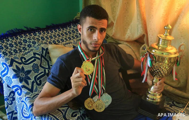 Palestinian football player Mohammed Abu Obaid, 26, who was shot in the leg by Israeli security forces during clashes in tents protest demanding the right to return to their homeland, at the Israel-Gaza border, lies on b...