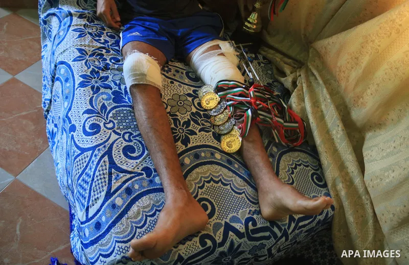 Palestinian football player Mohammed Abu Obaid, 26, who was shot in the leg by Israeli security forces during clashes in tents protest demanding the right to return to their homeland, at the Israel-Gaza border, lies on b...