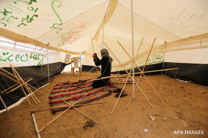 A masked Palestinian man prepares a kite to laden it with a molotov cocktail to use it during clashes with Israeli security forces at tents protest where Palestinians demand the right to return to their homeland, in east...