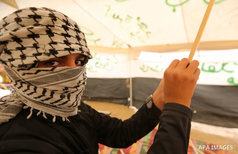 A masked Palestinian man prepares a kite to laden it with a molotov cocktail to use it during clashes with Israeli security forces at tents protest where Palestinians demand the right to return to their homeland, in east...