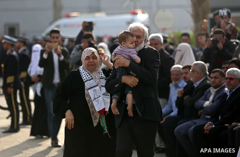 The son of Palestinian scientist Fadi al-Batsh, who was assassinated in Malaysia, is kissed by his grandfather as his father's body arrives at the Rafah border crossing in the southern Gaza Strip on April 26, 2018, after...