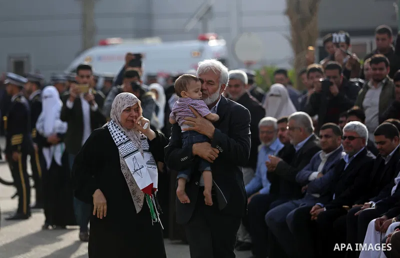 The son of Palestinian scientist Fadi al-Batsh, who was assassinated in Malaysia, is kissed by his grandfather as his father's body arrives at the Rafah border crossing in the southern Gaza Strip on April 26, 2018, after...