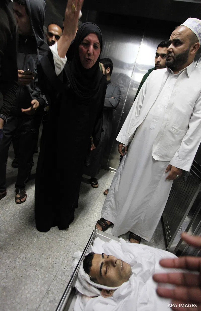 Relatives of Palestinian Mohammed Al-Maqid, 21, who was shot dead by Israeli security forces during clashes at the Israel-Gaza border, mourn over his body at a morgue in hospital in Gaza city, on April 27, 2018. Photo by...