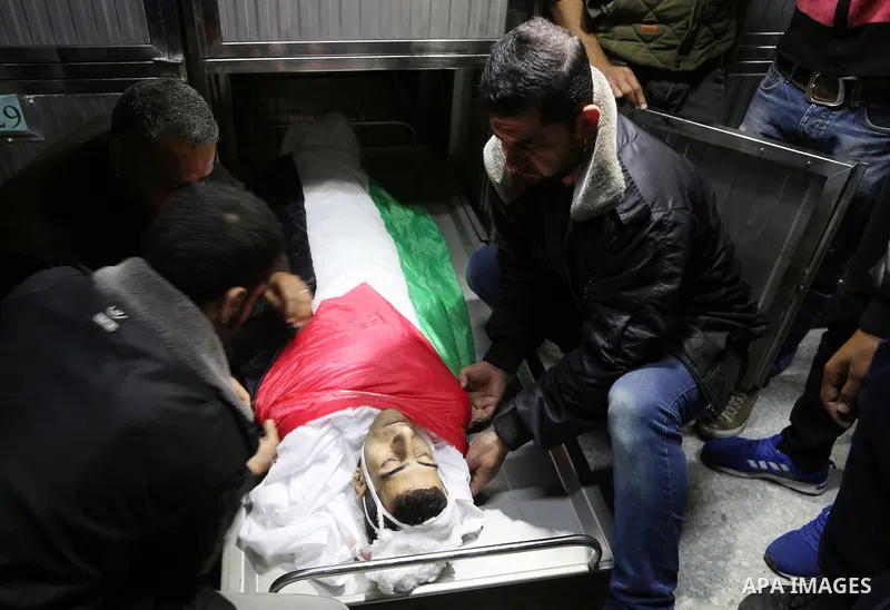Relatives of Palestinian Mohammed Al-Maqid, 21, who was shot dead by Israeli security forces during clashes at the Israel-Gaza border, cover his body with Palestinian flag during his funeral in Gaza city, on April 28, 20...
