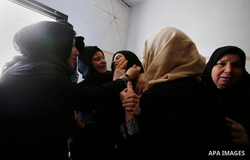 Palestinian women mourn over the body of 15-year-old Palestinian teenager Azzam Oweida who was died of his injuries sustained by Israeli security forces during clashes at the Israel-Gaza border, during his funeral in Kha...