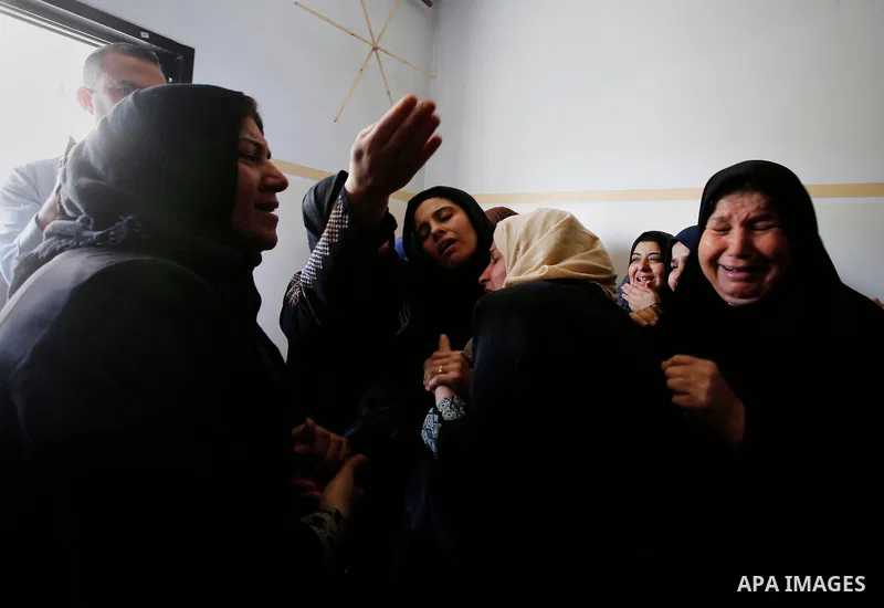 Palestinian women mourn over the body of 15-year-old Palestinian teenager Azzam Oweida who was died of his injuries sustained by Israeli security forces during clashes at the Israel-Gaza border, during his funeral in Kha...