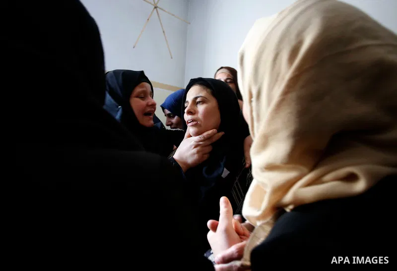 Palestinian women mourn over the body of 15-year-old Palestinian teenager Azzam Oweida who was died of his injuries sustained by Israeli security forces during clashes at the Israel-Gaza border, during his funeral in Kha...