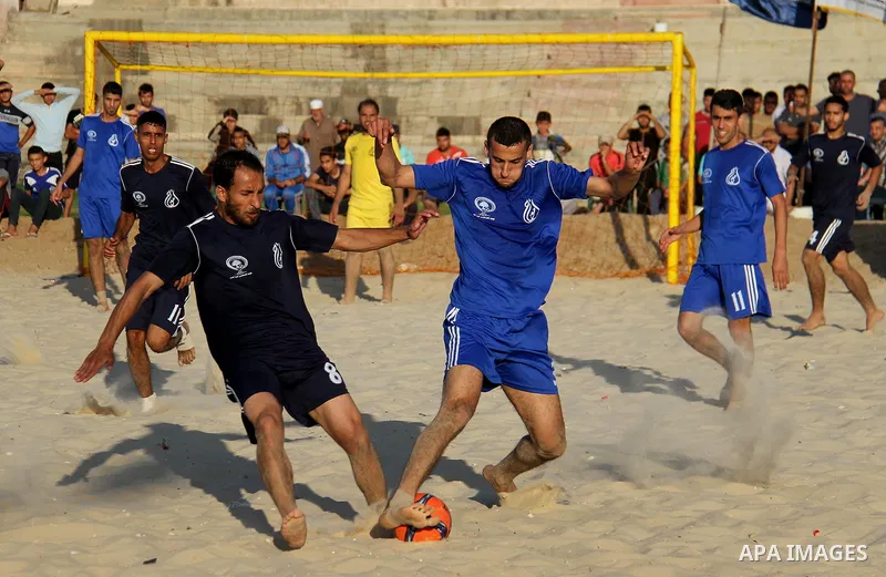 Palestinian players of Khadamat al-Shati club (blue) compete with players of al-Hilal club (Dark Blue) during the final football match of Beach Soccer Championship, in Gaza city on May 9, 2018. Photo by Mahmoud Ajour