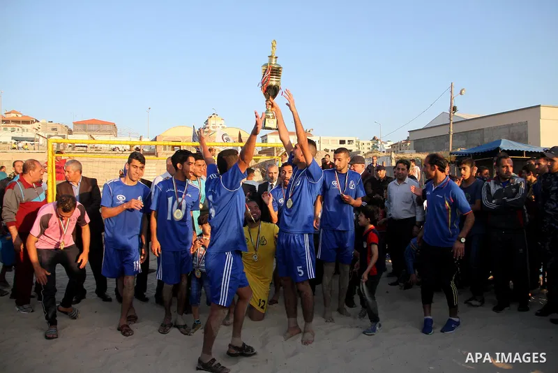 Palestinian players of Khadamat al-Shati club celebrate with Trophy after the beating al-Hilal club during the final football match of Beach Soccer Championship, in Gaza city on May 9, 2018. Photo by Mahmoud Ajour