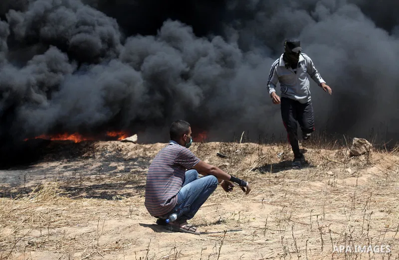Palestinian protesters gather during clashes with Israeli security froces in a tent city protest where Palestinians demand the right to return to their homeland, on the occasion of the 70th anniversary of the "Nakba", an...