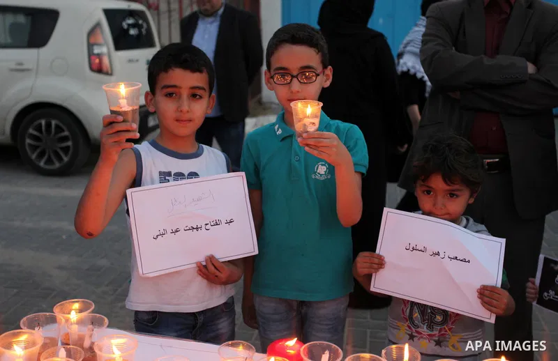 Palestinians light candles during a protest two days after at least 60 Palestinians were killed and 2,400 were injured including children, were shot and killed by Israeli soldiers as they gathered to demonstrate along th...