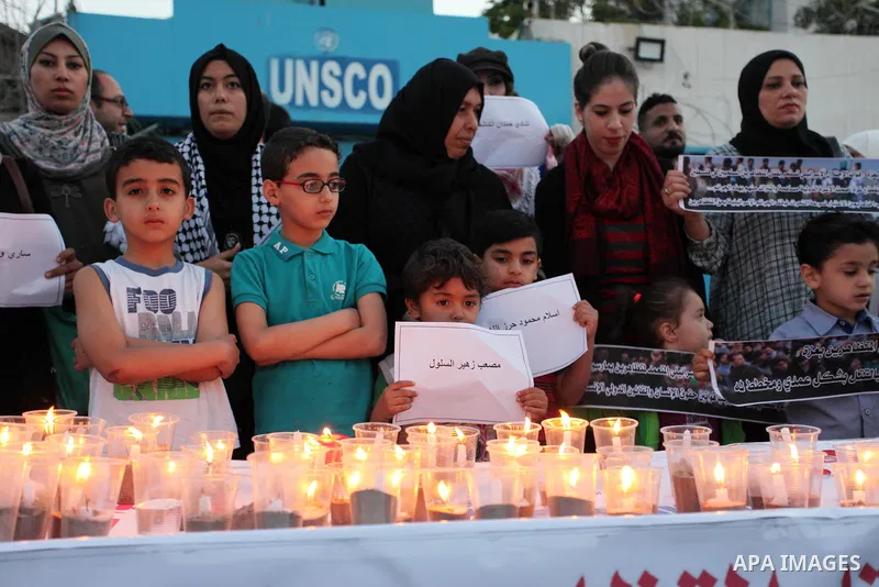 Palestinians light candles during a protest two days after at least 60 Palestinians were killed and 2,400 were injured including children, were shot and killed by Israeli soldiers as they gathered to demonstrate along th...