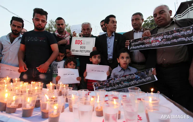 Palestinians light candles during a protest two days after at least 60 Palestinians were killed and 2,400 were injured including children, were shot and killed by Israeli soldiers as they gathered to demonstrate along th...