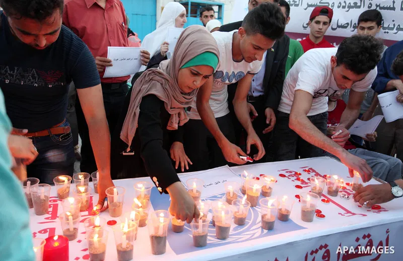 Palestinians light candles during a protest two days after at least 60 Palestinians were killed and 2,400 were injured including children, were shot and killed by Israeli soldiers as they gathered to demonstrate along th...