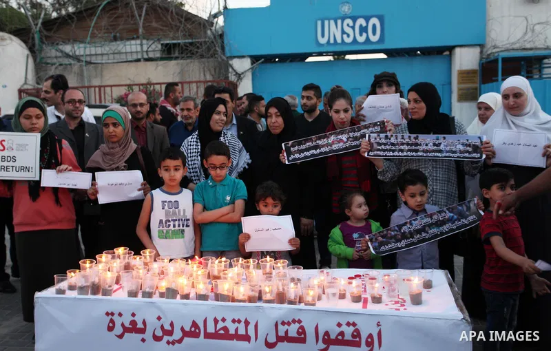 Palestinians light candles during a protest two days after at least 60 Palestinians were killed and 2,400 were injured including children, were shot and killed by Israeli soldiers as they gathered to demonstrate along th...