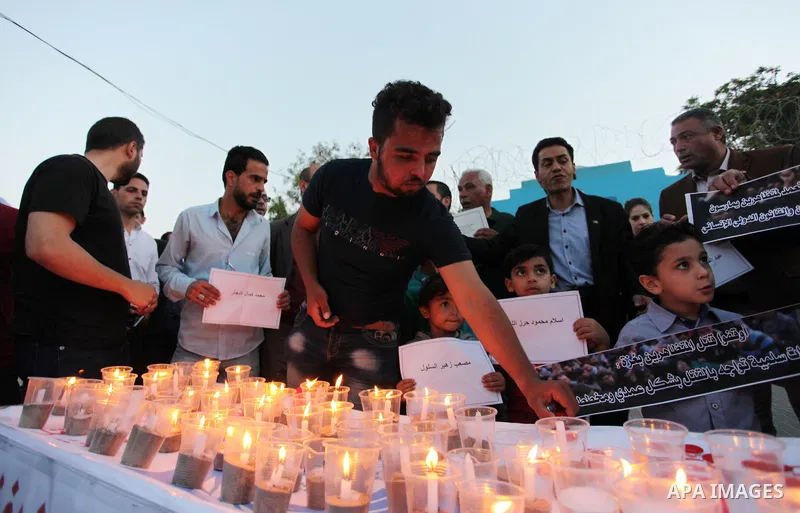 Palestinians light candles during a protest two days after at least 60 Palestinians were killed and 2,400 were injured including children, were shot and killed by Israeli soldiers as they gathered to demonstrate along th...