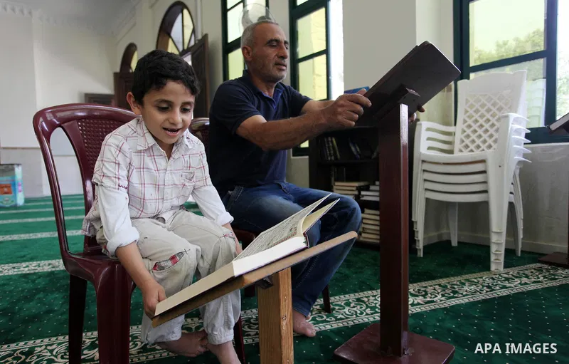 A Palestinian man and his boy read the Koran, Islam's holiest book, at a mosque in Gaza City on the Muslim holy month of Ramadan, on May 20, 2018. Ramadan is sacred to Muslims because it is during that month that traditi...