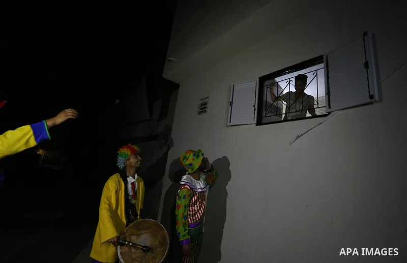 Palestinians dressed as clowns dawn awakener or Al Musaharati in Arabic, beat on their drums to wake Muslims for their overnight 'sahur', last meal, before the day's fast, as they walk through streets, in Dair Al Balah i...