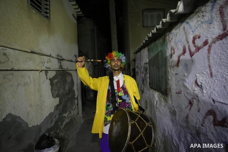 Palestinians dressed as clowns dawn awakener or Al Musaharati in Arabic, beat on their drums to wake Muslims for their overnight 'sahur', last meal, before the day's fast, as they walk through streets, in Dair Al Balah i...
