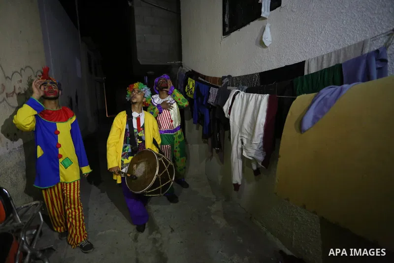 Palestinians dressed as clowns dawn awakener or Al Musaharati in Arabic, beat on their drums to wake Muslims for their overnight 'sahur', last meal, before the day's fast, as they walk through streets, in Dair Al Balah i...