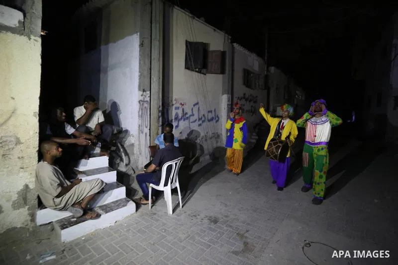 Palestinians dressed as clowns dawn awakener or Al Musaharati in Arabic, beat on their drums to wake Muslims for their overnight 'sahur', last meal, before the day's fast, as they walk through streets, in Dair Al Balah i...