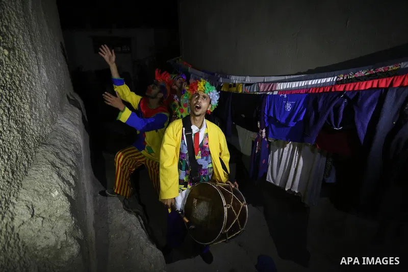 Palestinians dressed as clowns dawn awakener or Al Musaharati in Arabic, beat on their drums to wake Muslims for their overnight 'sahur', last meal, before the day's fast, as they walk through streets, in Dair Al Balah i...