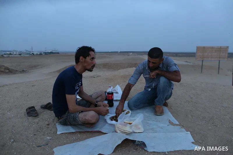 Palestinian men break their fast on the Muslim holy fasting month of Ramadan at the Israel-Gaza border, in east of Gaza city, on May 23, 2018. Ramadan is sacred to Muslims because it is during that month that tradition s...